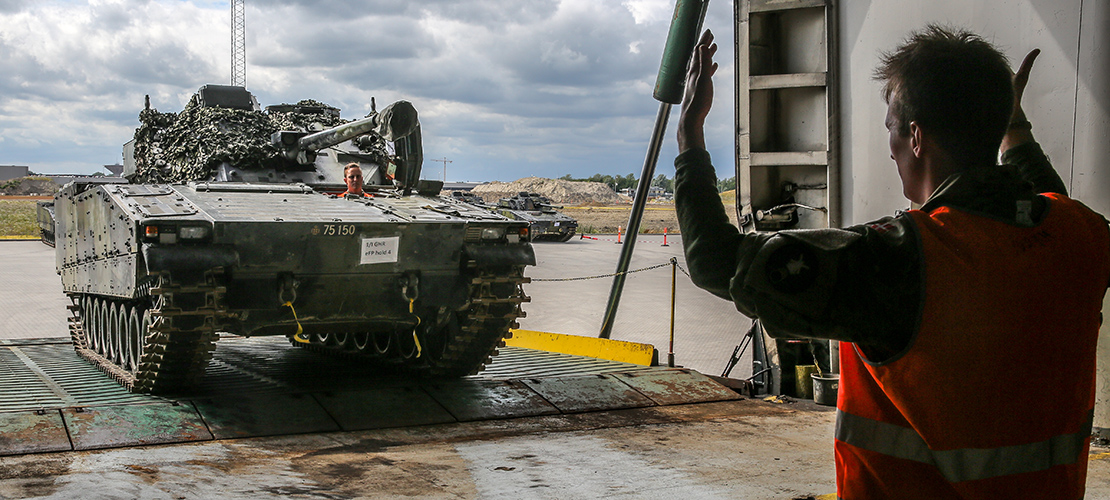 Personel fra JMTO sørger for at få et pansret køretøj sikkert ombord på et transportskib.