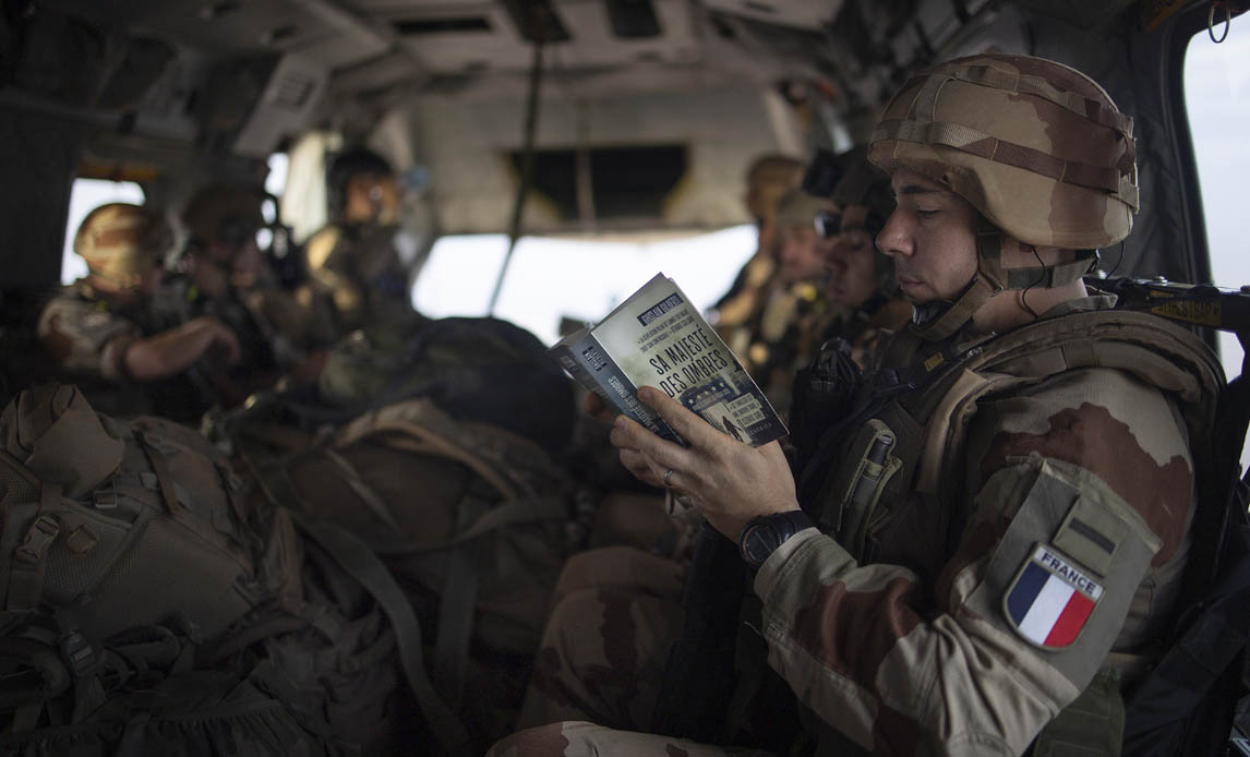 Fransk soldat læser bog under transport i dansk EH101 helikopter.