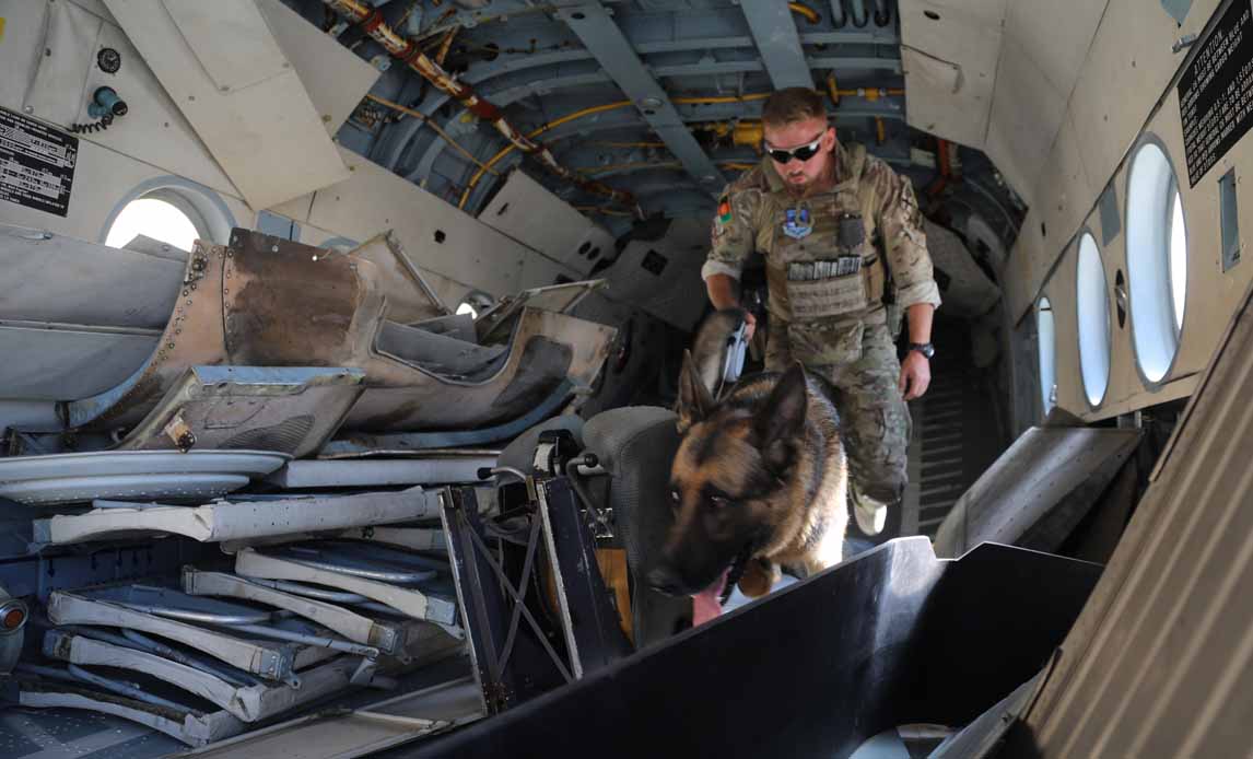 Hundefører og sprængstofshund afsøger MI-13 helikopter, inden den kan loades på cargoflyet.