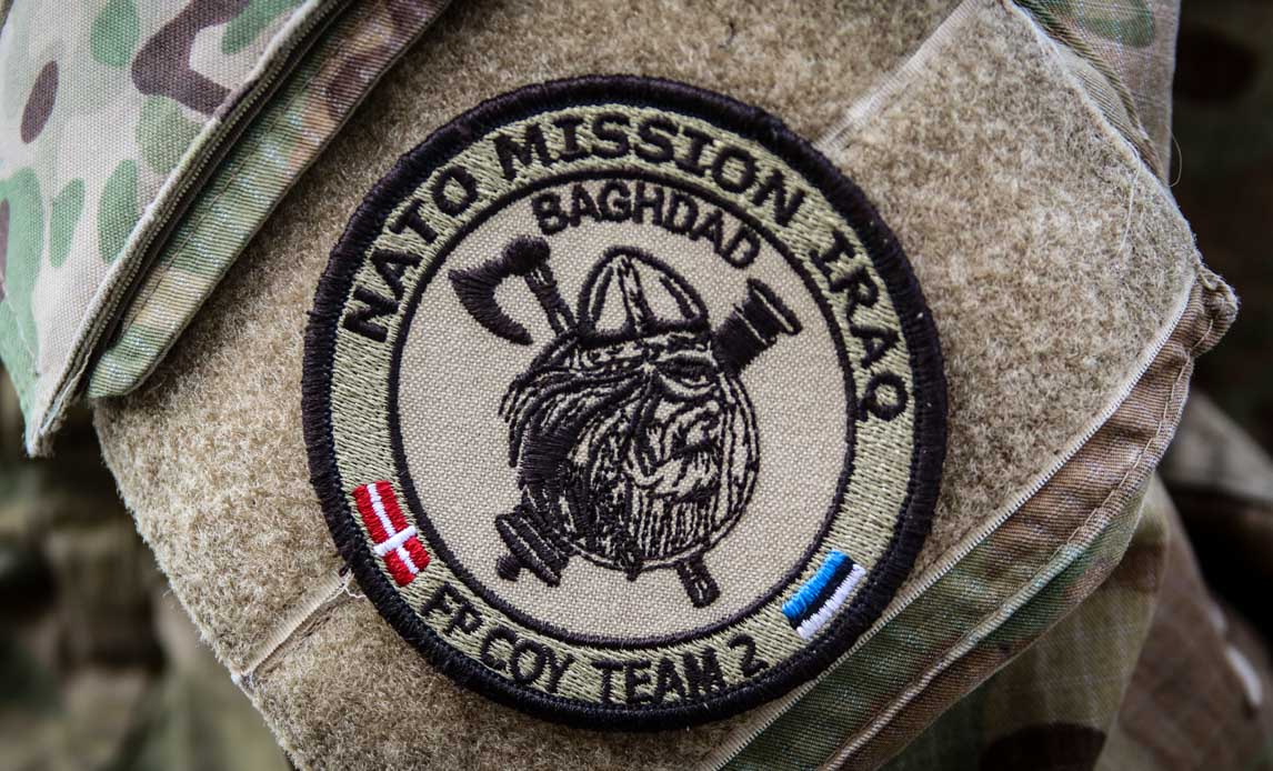 Ærmemærke, der viser NATO Mission Iraks logo og slogan.