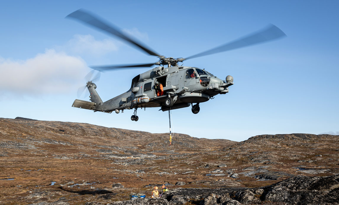 En Seahawk-helikopter hoister materiel fra inspektionsskibet Vædderen ind på landjorden, hvor Beredskabsstyrelsen bygger lejr.